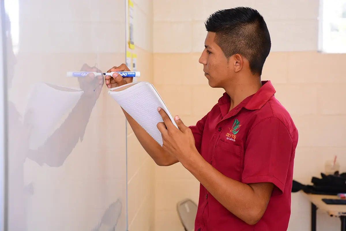 Schüler beim Schreiben an der Tafel im Klassenzimmer, Sinnbild für den Schulalltag im Schulsystem Costa Rica.